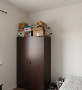 Espace vertical perdu et désordonné au-dessus d'un placard standard dans un petit appartement.